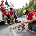 After a day of learning to fight fires, Everett firefighter recruit Chau Nguyen flakes a hose as other recruits load the hoses onto a fire truck at a training facility Thursday, April 19, 2018, on S. Machias Road in Snohomish. (Andy Bronson / The Herald)