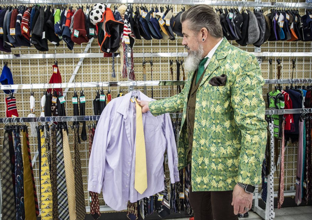 Tim Lambright tests out different tie colors with a lavender shirt while putting together a spring themed outfit at Value Village. (Olivia Vanni / The Herald)