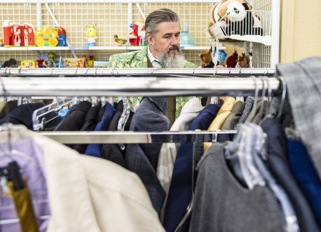 Tim Lambright browses the mens suit jackets while putting together a spring themed outfit at Value Village. (Olivia Vanni / The Herald)