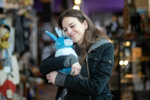 Danie Hadsall hugs a Lunar Jackalope of her own creation on Thursday, April 6, 2023, at Artisans PNW in Everett, Washington. Hadsall is running a kickstarter with a goal of $5,000 to get the jackalope into the hands of buyers. (Ryan Berry / The Herald)