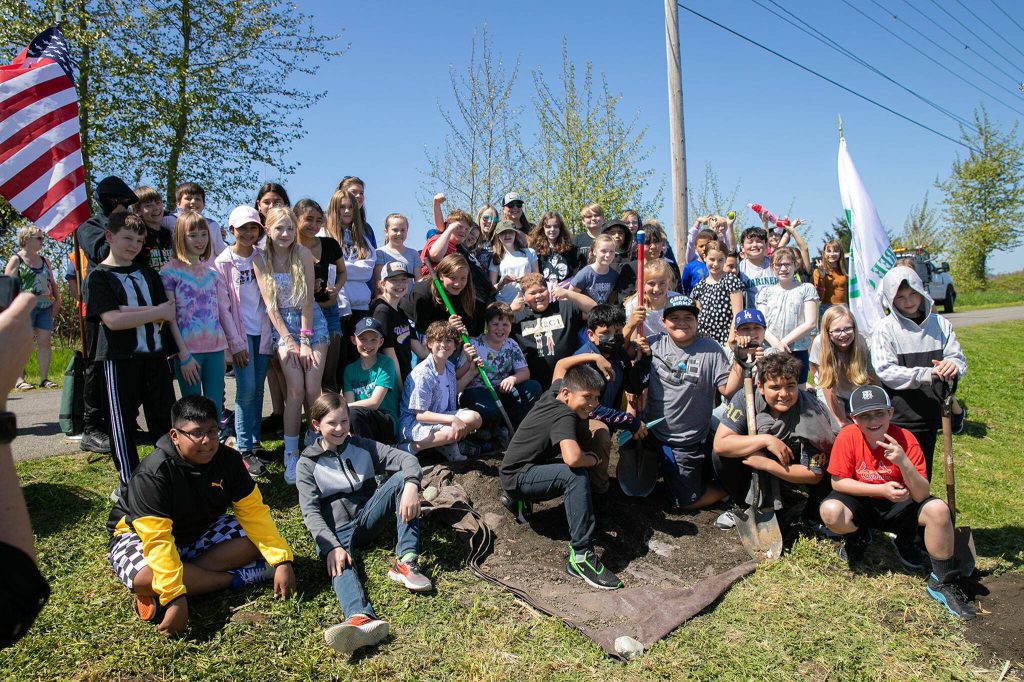 Freylands Elementary fifth graders from Mrs. Sager and Mrs. Slaters classrooms take a group photo after planting a tree during an Arbor Day celebration at Lake Tye Park on Friday, April 28, 2023, in Monroe, Washington. (Ryan Berry / The Herald)