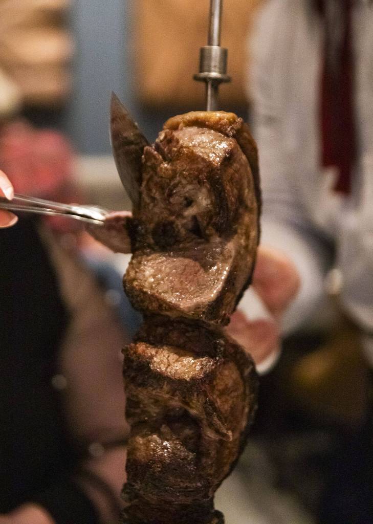 A top sirloin is cut into pieces by a gaucho to be served at Fogo de Chão on Thursday, April 20, 2023 in Lynnwood, Washington. (Olivia Vanni / The Herald)