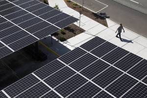 A man walks past a parking lot roof made up of solar panels at Hopeworks Station on Monday, Aug. 31, 2020 in Everett, Washington. (Andy Bronson / The Herald)