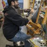 Bruce Rivera, 38, paints at Graphite Arts Center in Edmonds, Washington on Saturday, April 15, 2023. A silent auction of skateboard art will be held to raise money to kick-start Riveras new nonprofit, Salvage Arts. (Annie Barker / The Herald)