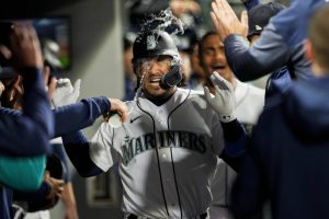 Seattle Mariners' Eugenio Suarez has water thrown at him in the dugout after his home run against the Colorado Rockies during the fourth inning of a baseball game Saturday, April 15, 2023, in Seattle. (AP Photo/Lindsey Wasson)