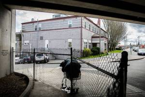 A full shopping cart full of items is left unattended outside of the Everett Gospel Mission along a fence put in place due the current no sit no lie ordinance on Tuesday, April 18, 2023 in Everett, Washington. (Olivia Vanni / The Herald)