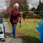 Toni Kief and her cat, Poppy, 5, smiles as she is handed a bird feather that she collects while she picks up trash on Tuesday, April 18, 2023 in Marysville, Washington. (Olivia Vanni / The Herald)