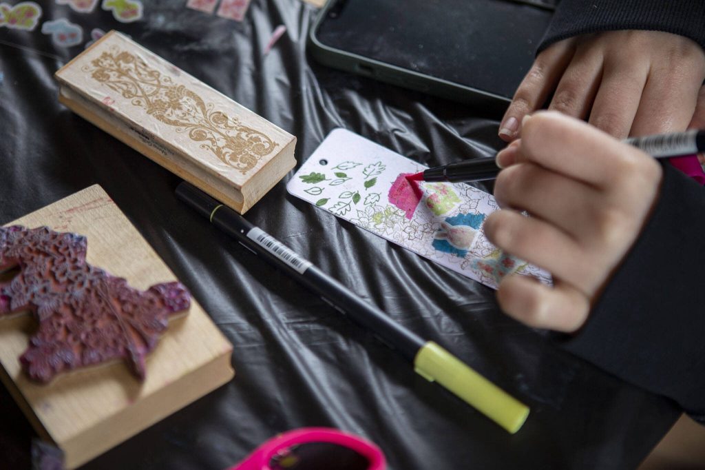 Vida Pourhashem, 24, colors a bookmark during the Cascadia Tea spring festival at Floral Hall in Everett, Washington on Saturday, April 15, 2023. (Annie Barker / The Herald)