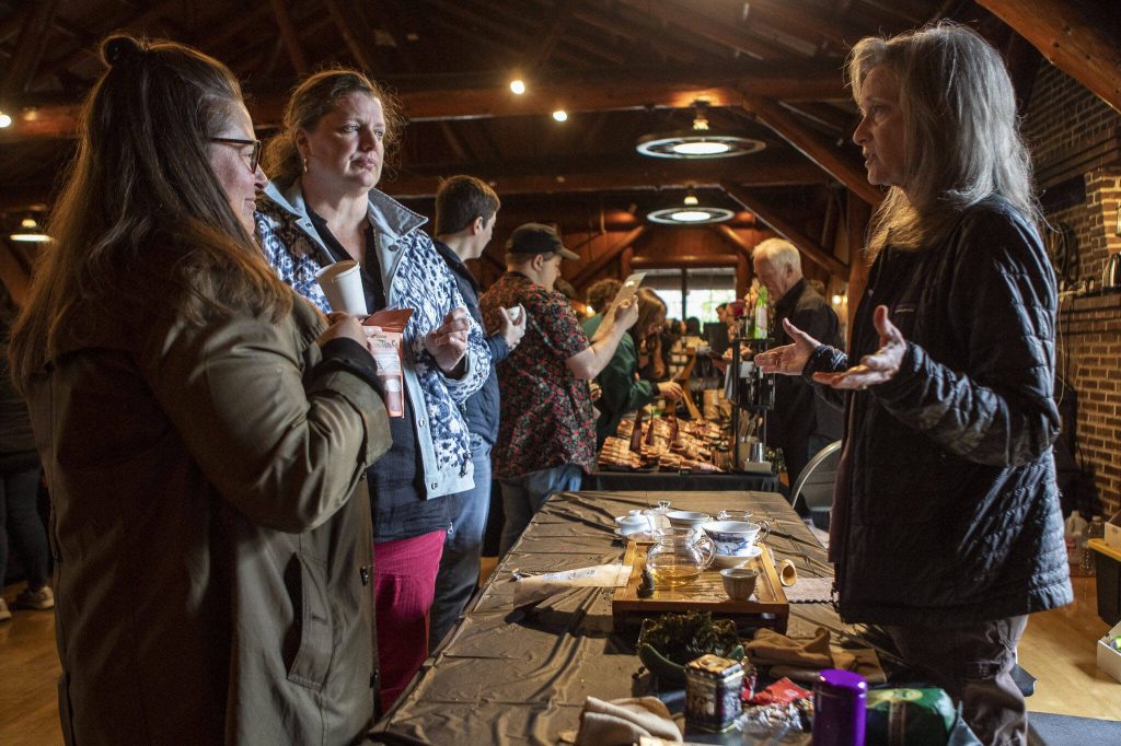 Joan Chissus, right, talks to attendees about oolong tea during the Cascadia Tea spring festival at Floral Hall in Everett, Washington on Saturday, April 15, 2023. (Annie Barker / The Herald)