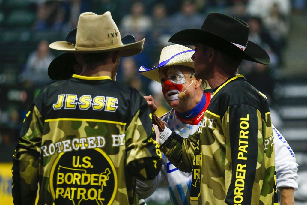 Rodeo Clown Flint Rasmussen huddles with the U.S. Border Patrol during Unleash The Beast at Angel of the Winds Arena in Everett, Washington on Thursday, April 20, 2023. (Annie Barker / The Herald)