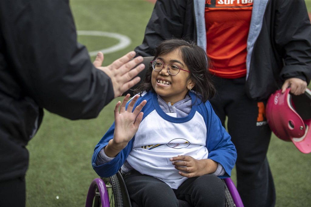 Ananya Raghavan, 10, gives a high-five during a game of YMCAs Miracle League Baseball at Monroe Rotary Field in Monroe, Washington on Saturday, April 22, 2023. The program is designed to allow people with diverse abilities to play baseball. (Annie Barker / The Herald)