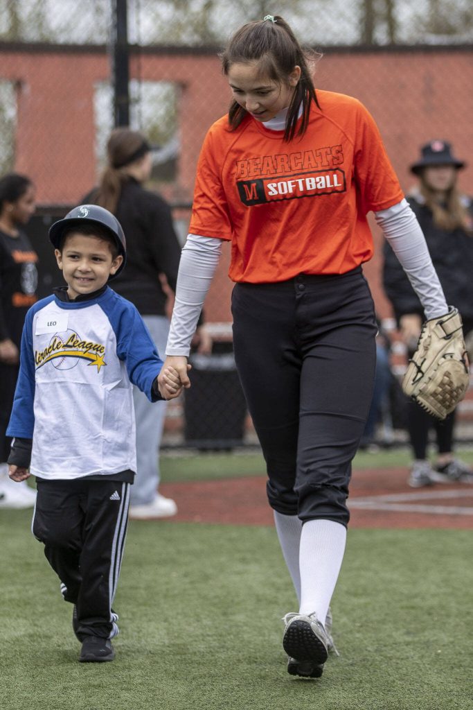 Leo Baca-Cortez, 5, left, and Brooke Boswell, right, walk together during a game of YMCAs Miracle League Baseball at Monroe Rotary Field in Monroe, Washington on Saturday, April 22, 2023. The program is designed to allow people with diverse abilities to play baseball. (Annie Barker / The Herald)
