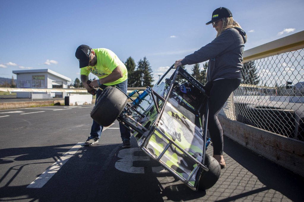 Matt Stone, left, checks on one of Aiden Stones, 8, center, racecars with the help of Angela Stone, right, at Evergreen Fairgrounds in Monroe, Washington on Tuesday, April 25, 2023. (Annie Barker / The Herald)