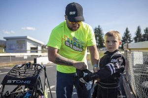 Matt Stone, left, helps Aiden Stone, 8, right, remove gloves at Evergreen Fairgrounds in Monroe, Washington on Tuesday, April 25, 2023. (Annie Barker / The Herald)