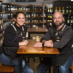 Owners Krista and Eric Brown sit among rows of wines at The Grape & Grain, a new independent beer and wine store on Evergreen Way, on Wednesday, April 28, 2021 in Everett, Washington. (Andy Bronson / The Herald)
