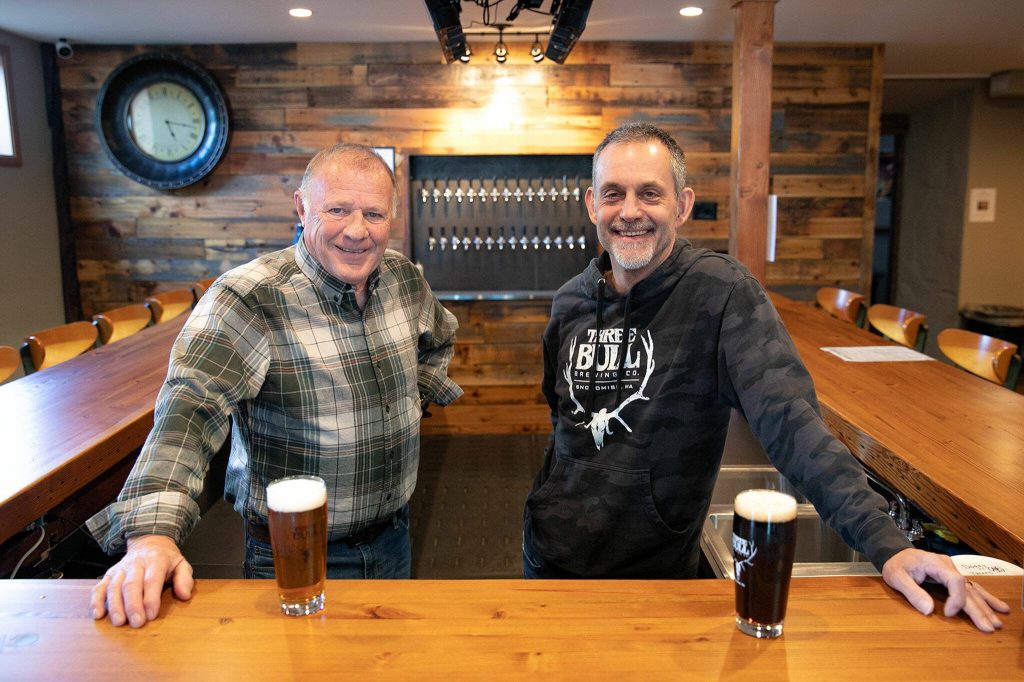 Big Bull Gary Pritzkau and his son Cary Pritzkau, who are two of multiple people involved in the operation of Three Bull Brewing, stand behind the bar at their new tap house on Wednesday, April 19, 2023, in downtown Snohomish, Washington. (Ryan Berry / The Herald)
