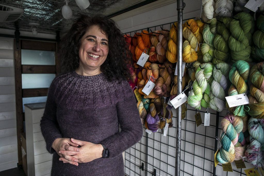 Willow Mietus, 50, poses for a photo with her dyed yarn at her home in Coupeville, Washington on Wednesday, Feb. 1, 2023. Mietus bought a former Frito-Lay truck to sell her yarn out of. She calls it The Wool Wagon. (Annie Barker / The Herald)
