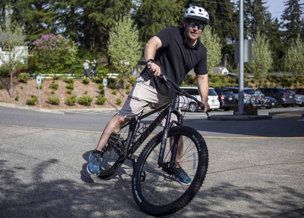 Edmonds Mayor Mike Nelson hops on a bike during Bike to School Day. (Annie Barker / The Herald)