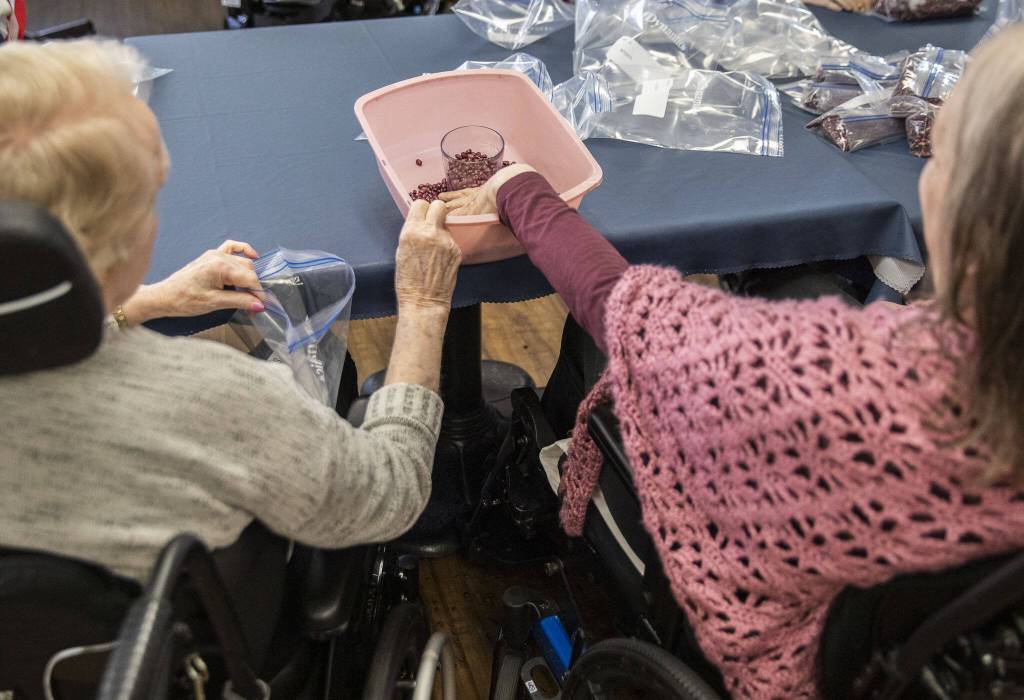 Marilyn Naylor, left, helps Katherine Audas fill a bag with dry beans on Tuesday, May 2, 2023 in Everett, Washington. (Olivia Vanni / The Herald)