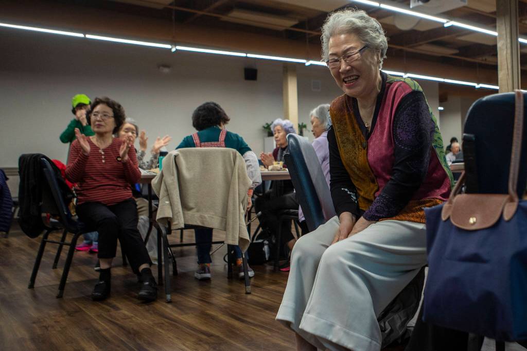Attendees smile and clap during karaoke while at a senior community meals program focused on the Korean community at Homage in Lynnwood, Washington on Thursday, May 4, 2023. (Annie Barker / The Herald)