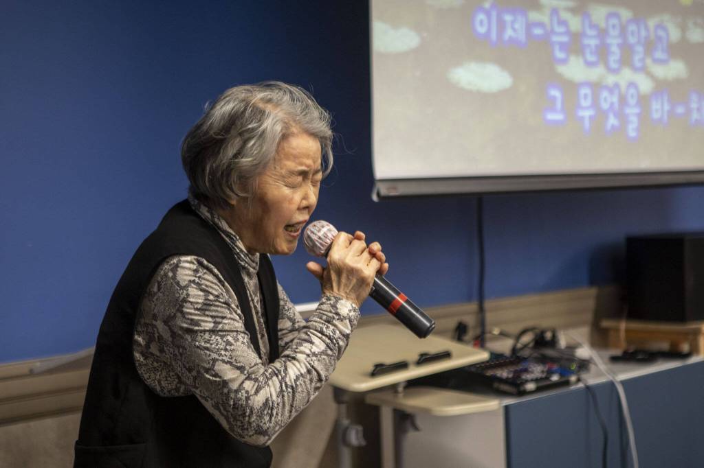Sung Lee sings during a senior community meals program focused on the Korean community at Homage in Lynnwood, Washington on Thursday, May 4, 2023. (Annie Barker / The Herald)