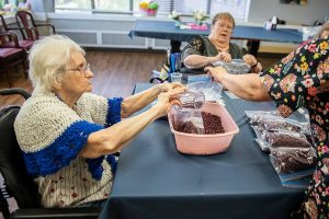 A group of Bethany senior residents fill bags with dry goods for the Faith Food Bank on Tuesday, May 2, 2023 in Everett, Washington. (Olivia Vanni / The Herald)