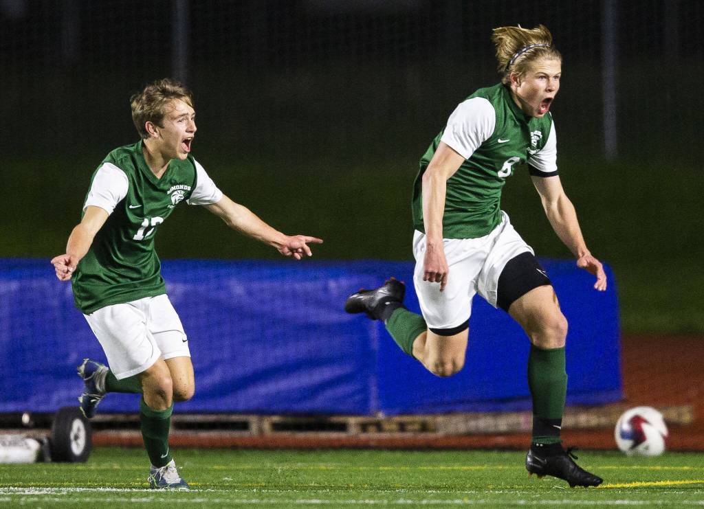 Edmonds-Woodways Kincaid Sund (8) and teammate Alex Plumis celebrate beating Everett to end their regular season undefeated on Monday in Edmonds. (Olivia Vanni / The Herald)