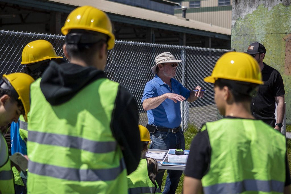 Riis Hotson talks about surveying during a trade fair at the Evergreen State Fairgrounds in Monroe, Washington on Wednesday, May 3, 2023. High school kids learned about various trades at the event. (Annie Barker / The Herald)