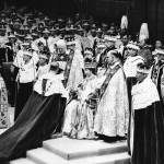Surrounded by his clerics and ladies-in-waiting, Queen Elizabeth II sits in the Chair of Estate in Westminster Abbey, London on June 2, 1953, before being crowned.     In royal gallery in background, Queen mother Elizabeth is leaning over to attend to the unseen little Prince Charles.    Princess Margaret also lends a hand.   Duchess of Gloucester may be seen at right in royal gallery. (AP Photo)