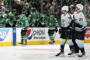 The Stars Wyatt Johnston (53) and Colin Miller (6) celebrate with the bench after Johnston scored as the Krakens Ryan Donato (9) and Alex Wennberg (21) skate past in the second period of Game 2 of second-round playoff series Thursday in Dallas. (AP Photo/Tony Gutierrez)