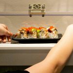 Levi Arneson, 12, grabs a roll from the monorail system next to his table at Sushi Hana on Jan. 5, in Lynnwood. (Ryan Berry / The Herald)