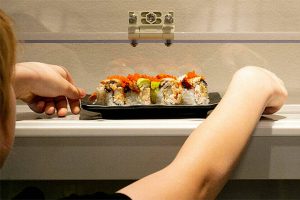 Levi Arneson, 12, grabs a roll from the monorail system next to his table at Sushi Hana on Jan. 5, in Lynnwood. (Ryan Berry / The Herald)