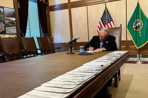 Washington Gov. Jay Inslee signs bills at the Washington State Capitol, Tuesday, May 9, 2023, in Olympia, Wash. One of those bills was Senate Bill 5599, which was designed to protect young people seeking reproductive health services or gender-affirming care. (AP Photo/Ed Komenda)