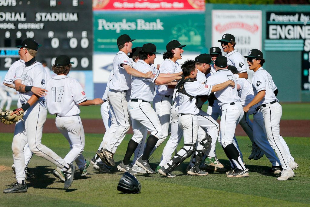 Jackson players mob sophomore pitcher Sam Craig after he struck out the final batter in a complete game shutout victory over Lake Stevens in a Wesco 4A District 1/2 game on Thursday, May 11, 2023, at Funko Field in Everett, Washington. (Ryan Berry / The Herald)