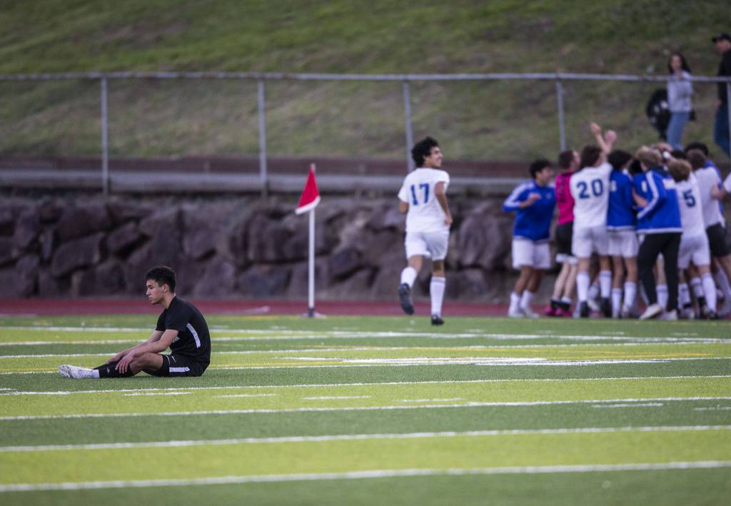 Jacksons Dylan Crosby sits on the ground as Bothell celebrates in the background after scoring the game winning goal off of a penalty kick in the second half of overtime on Thursday, May 11, 2023 in Everett, Washington. (Olivia Vanni / The Herald)