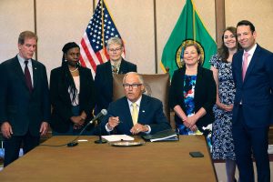 Gov. Jay Inslee signs Senate Bill 5536 concerning controlled substances on Tuesday, May 16, 2023, in Olympia, Wash. Behind him are from left to right: Rep. Roger Goodman, D- Kirkland, Rep. Jamila Taylor, D-Federal Way, House Speaker Laurie Jinkins, D-Tacoma, June Robinson, D-Everett, an identified woman and Andy Billig, D-Spokane. The policy, approved by Washinton lawmakers and signed by Inslee, keeps controlled substances illegal while boosting resources to help those struggling with addiction.  (Karen Ducey/The Seattle Times via AP)