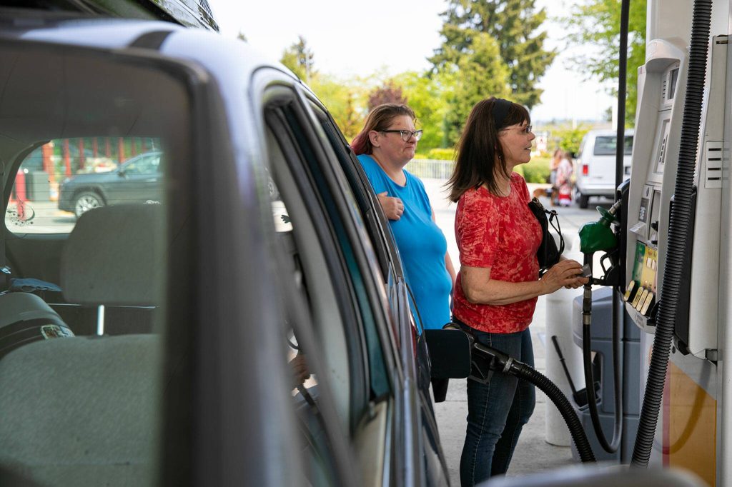 Penelope Protheroe, President and Founder of Angel Resource Connection, fills up the tank on Pam Flowers car on Wednesday, May 17, 2023, in Everett, Washington. (Ryan Berry / The Herald)