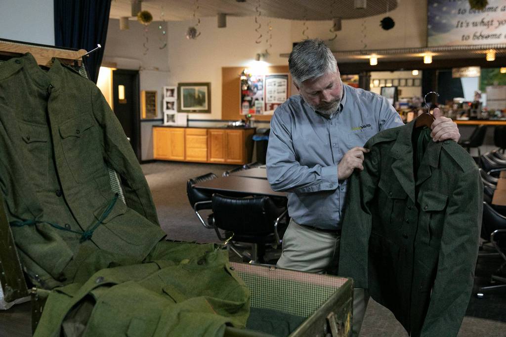 Tyler Austin, of Paul Davis Restoration and VFW Post 2100, removes old wool military uniforms from a chest that was stored in the VFWs basement on Friday, May 26, 2023, in Everett, Washington. (Ryan Berry / The Herald)