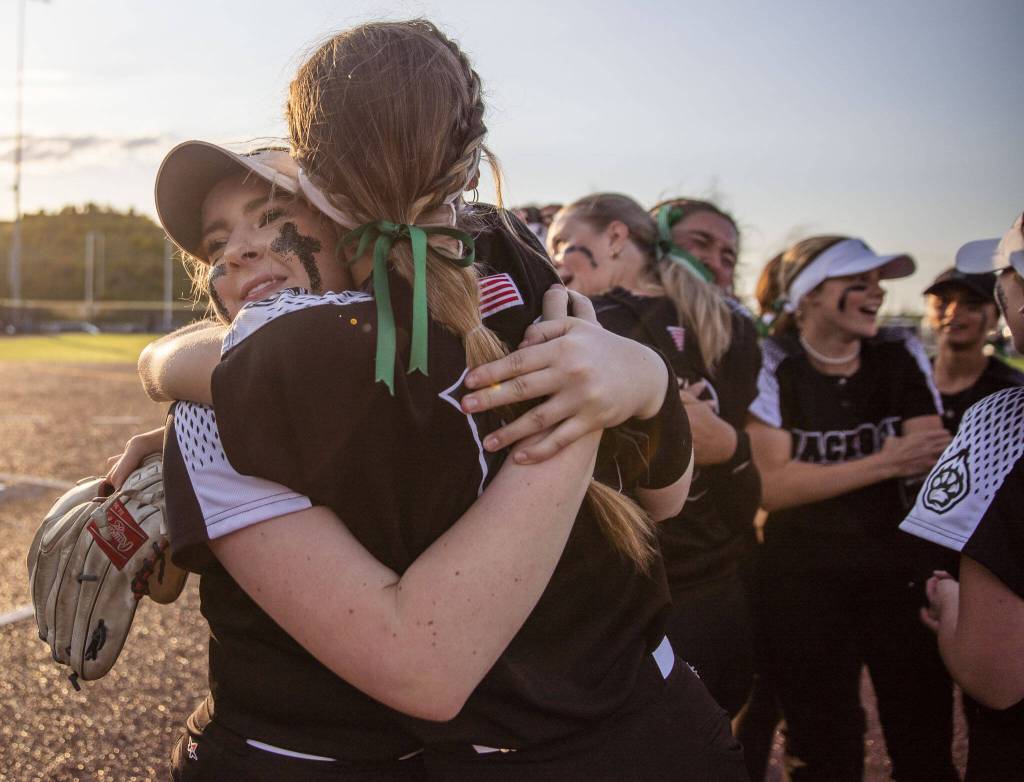 Jacksons Hailey Pelletier hug a teammate after beating Bothell to become the 3A district champions on Friday, May 19, 2023 in Everett, Washington. (Olivia Vanni / The Herald)