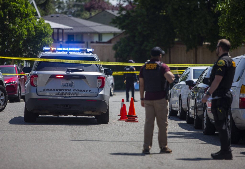 Police stand along Linden Street next to orange cones marking pullet casings in a crime scene of a police involved shooting on Friday, May 19, 2023 in Everett, Washington. (Olivia Vanni / The Herald)