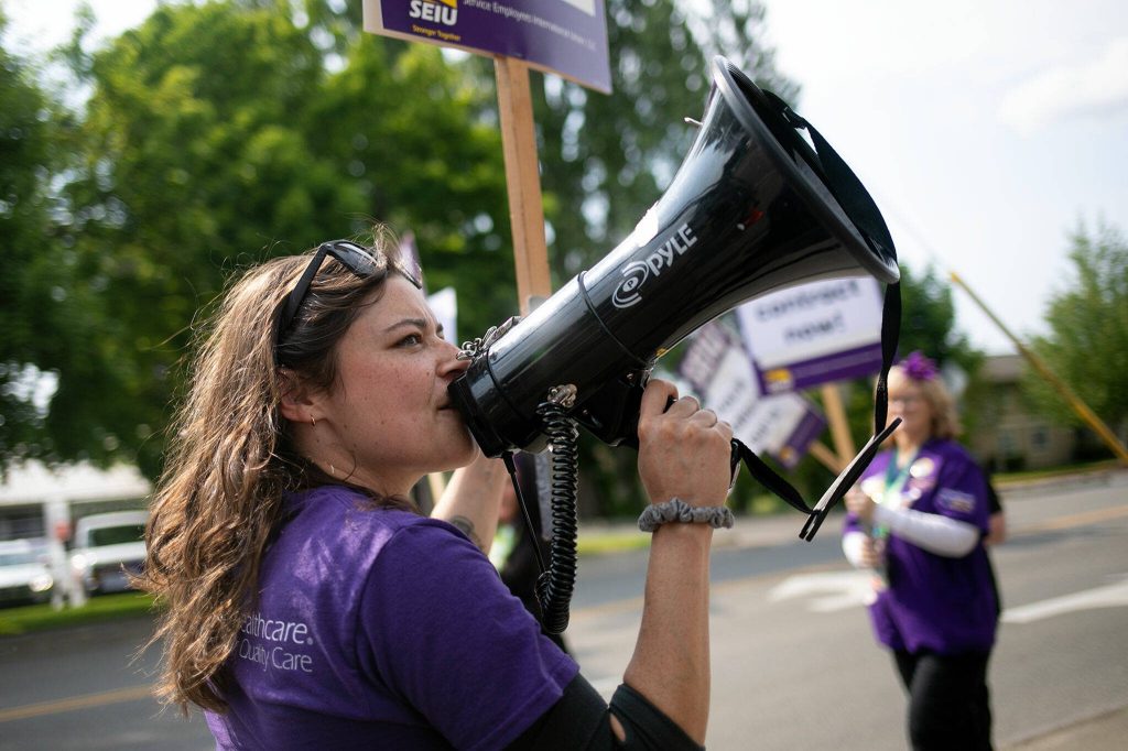 SEIU Healthcare 1199NW organizer Amber Fletcher leads a call and response while picketing during a union protest in front of EvergreenHealth Monroe on Wednesday, May 24, 2023, in Monroe, Washington. (Ryan Berry / The Herald)