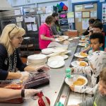 Students arriving off the bus get in line to score some waffles during a free pancake and waffle breakfast at Lowell Elementary School on Friday, May 26, 2023, in Everett, Washington. (Ryan Berry / The Herald)