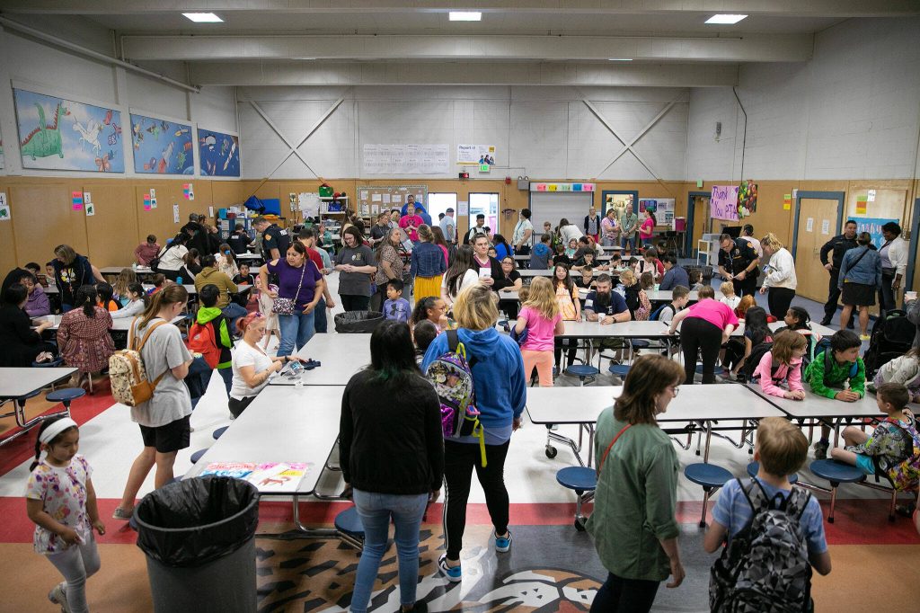 Students, teachers, parents and first responders mill about and snack on pancakes and waffles during a free pancake breakfast at Lowell Elementary School on Friday, May 26, 2023, in Everett, Washington. (Ryan Berry / The Herald)