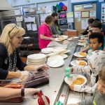 Students arriving off the bus get in line to score some waffles during a free pancake and waffle breakfast at Lowell Elementary School on Friday, May 26, 2023, in Everett, Washington. (Ryan Berry / The Herald)