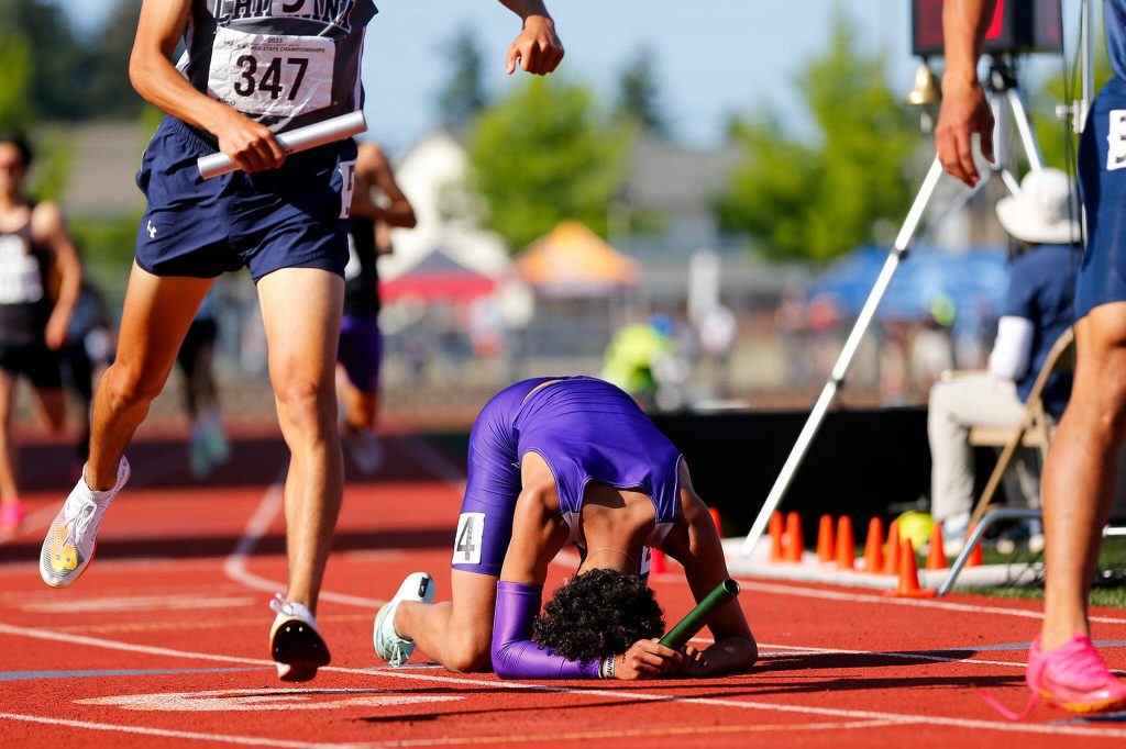 Lake Stevens senior Grant Buckmiller collapses to the ground after overcoming the leader on the final lap of the 4A boys 4x400 meter relay to claim first place for his team during the WIAA State Track and Field Championships on Saturday, May 27, 2023, at Mount Tahoma High School in Tacoma, Washington. (Ryan Berry / The Herald)