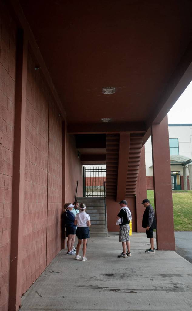 Jackson and Glacier Peak coaches discuss the WIAA 4A title game storm delay with Adrian Ochoa, Richland High School athletic director, resulting in both schools calling the game final in the 6th inning, resulting in Jackson winning the 2023 WIAA Class 4A softball championship on Saturday, May 27, 2023, in Richland. (TJ Mullinax / For The Herald)