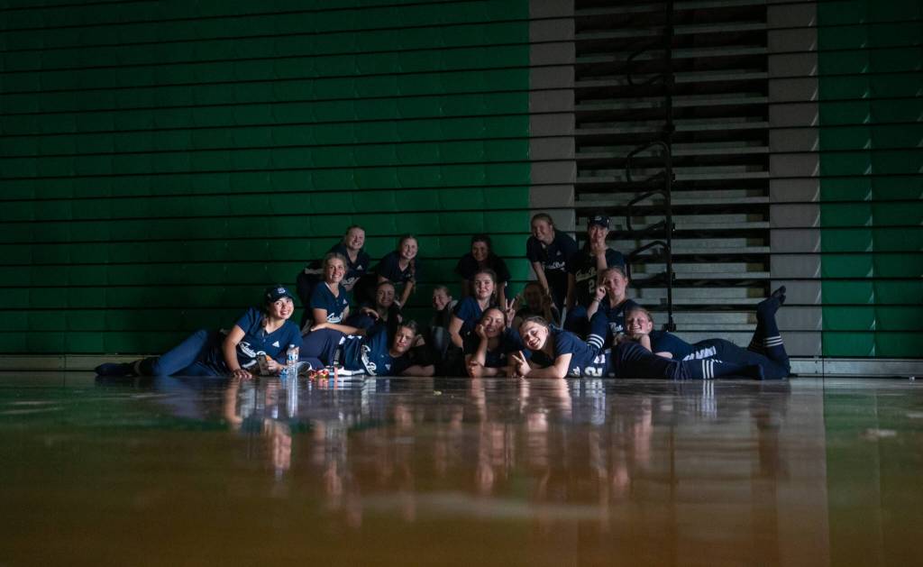 While waiting out a lightning and rain delay, Glacier Peak players pose in an unlit gymnasium during the WIAA Class 4A state softball title game on Saturday, May 27, 2023, in Richland. (TJ Mullinax / For The Herald)