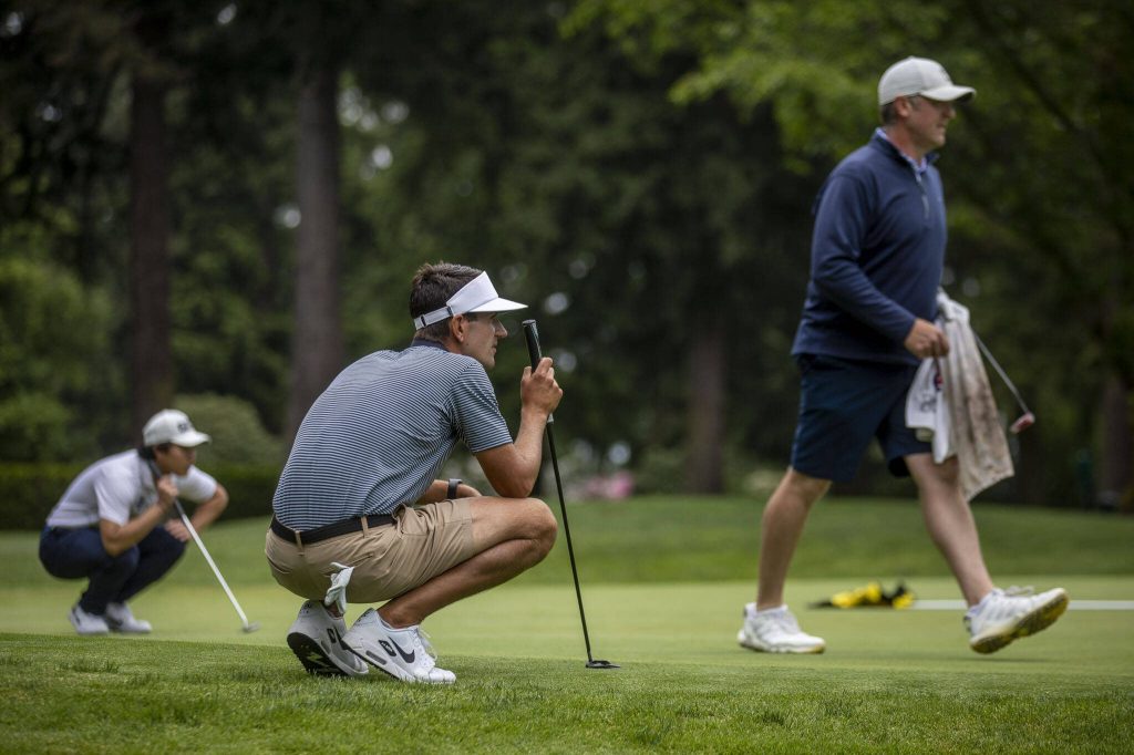 Johnny Carey, center, inspects the green during the Snohomish County Amateur golf tournament at the Everett Golf and Country Club in Everett, Washington on Monday, May 29, 2023. (Annie Barker / The Herald)