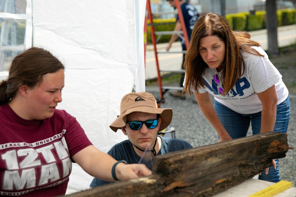 Instructional Assistant Professor Katie Custer Bojakowski, of Texas A&Ms Nautical Archaeology Program, right, speaks with students Shelby Hiatt and Parker Burris, center, as they take measurements of a separated piece of the Equator on Wednesday, June 7, 2023, during a two-week survey of the vessel at its resting place in Everett, Washington. (Ryan Berry / The Herald)