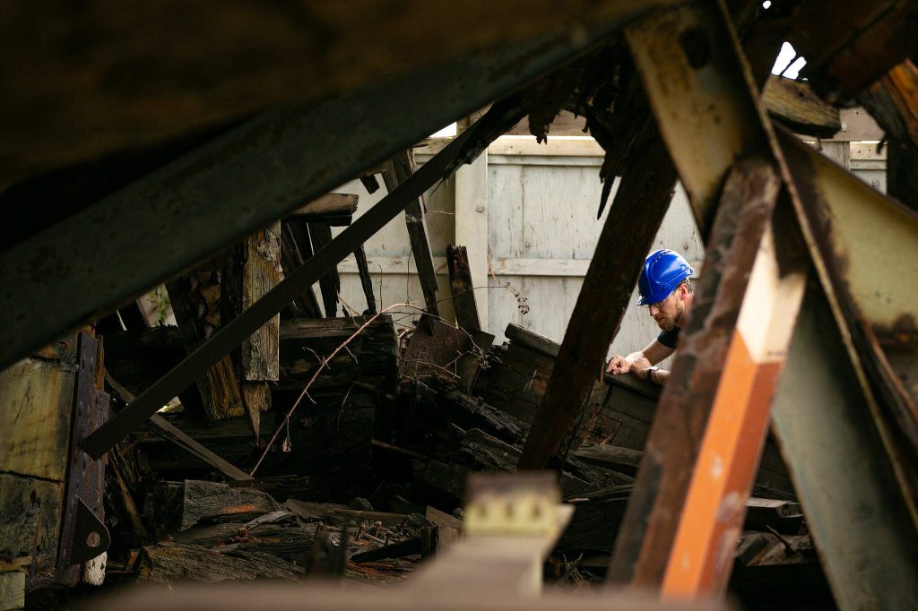 Nathaniel Howe, a nautical archaeologist based in the Seattle area, inspects the collapsed stern of the Equator on Wednesday, June 7, 2023, during a two-week survey of the vessel at its resting place in Everett, Washington. Howe joined the project as a collaborator with the staff and students from Texas A&M. (Ryan Berry / The Herald)